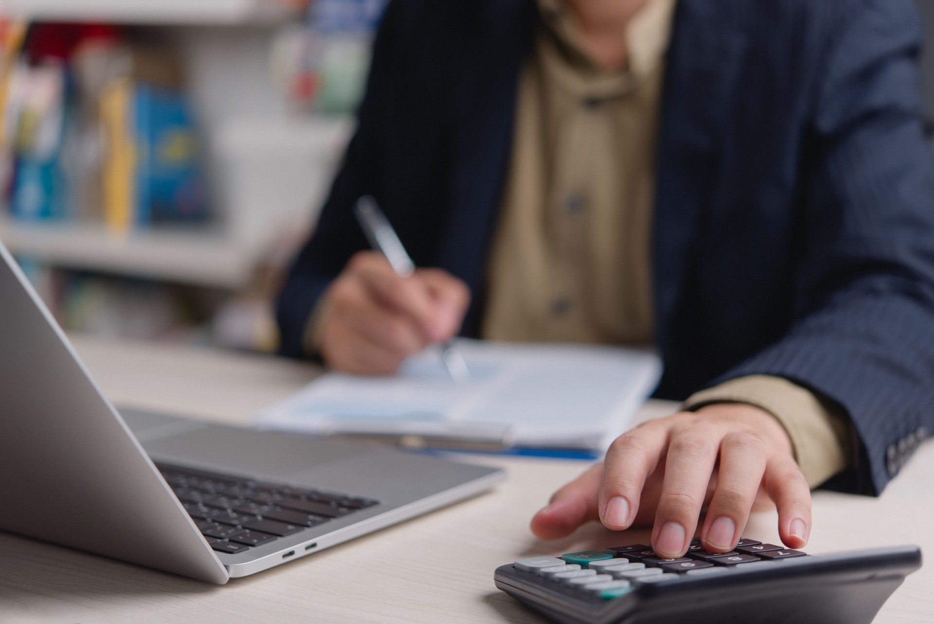 Man working on financial paperwork and using calculator, representing corporate accounting and budgeting strategy.